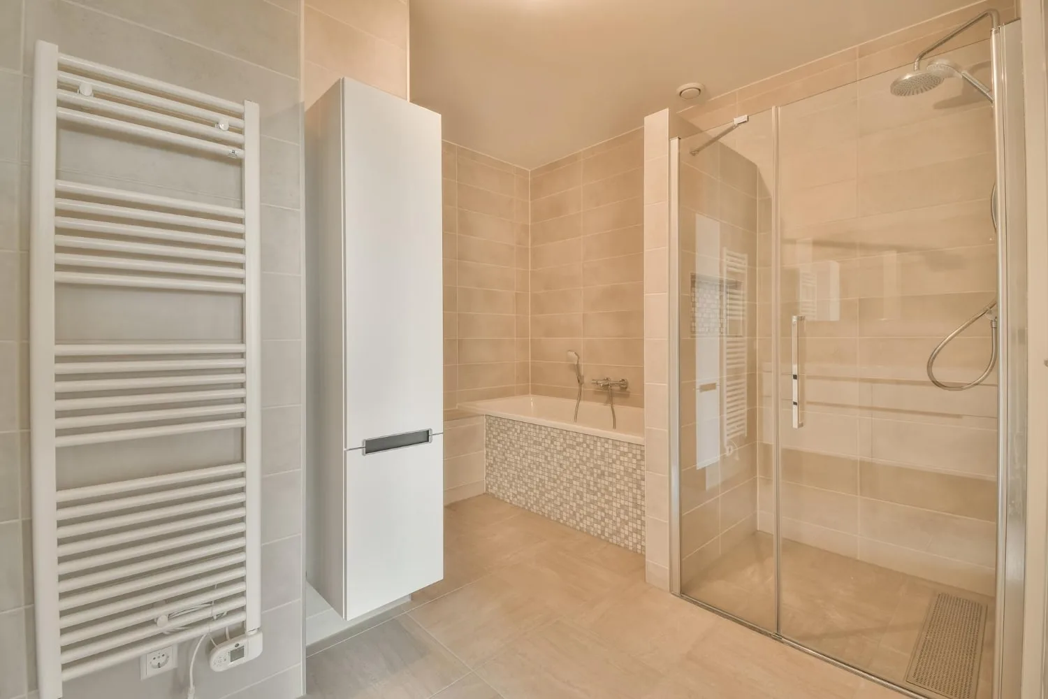 Douche à l’italienne lumineuse avec paroi en verre fixe, robinetterie noire, niche murale et caniveau de douche discret.