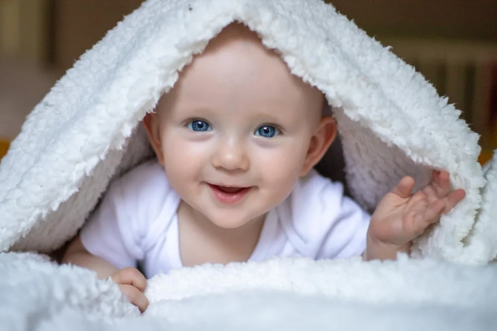 Parent préparant une petite baignoire stable pour donner le bain à un bébé dans une douche italienne propre et sécurisée.