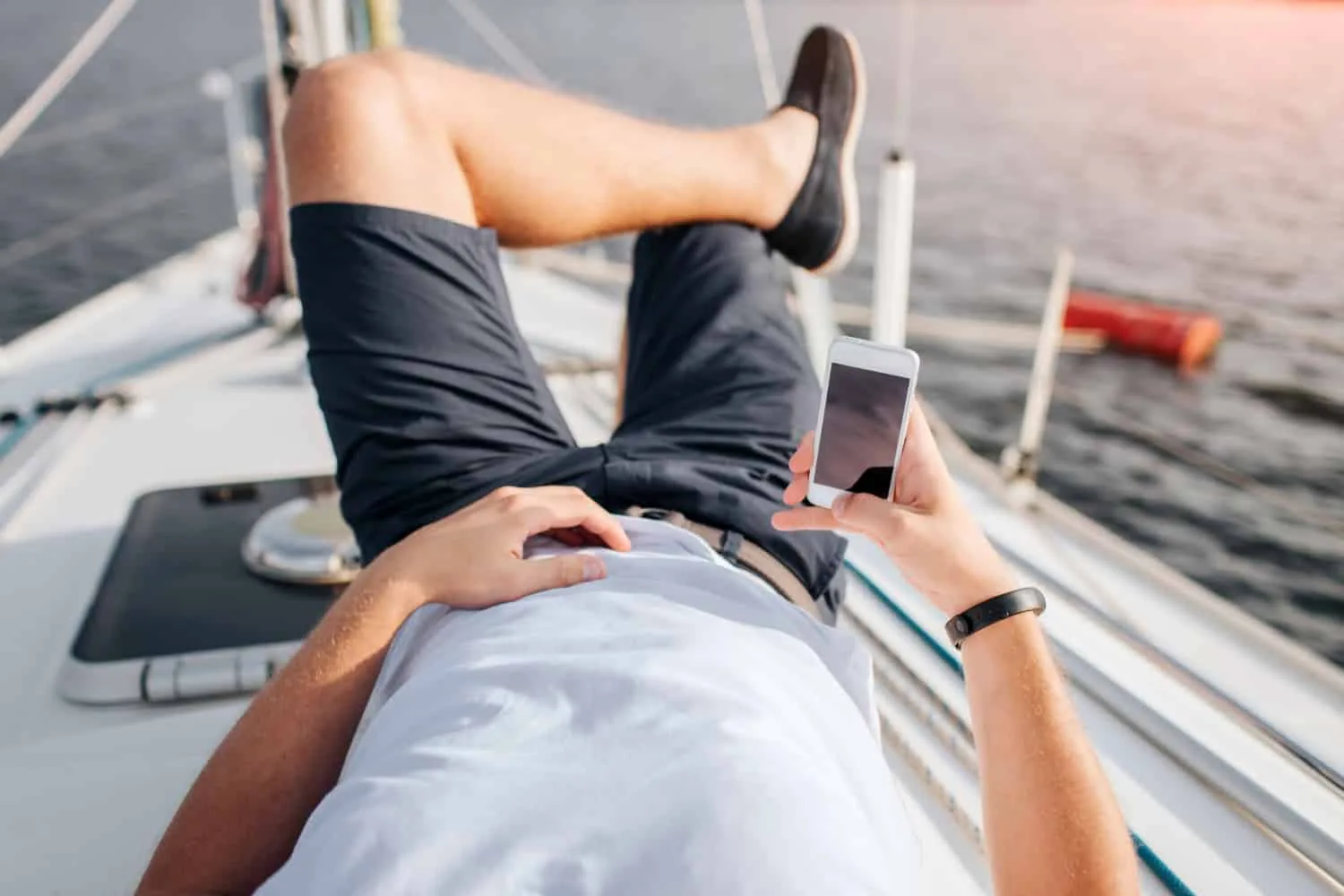 Paire de chaussures bateau en cuir marron portée avec un pantalon clair, sur un ponton en bois.