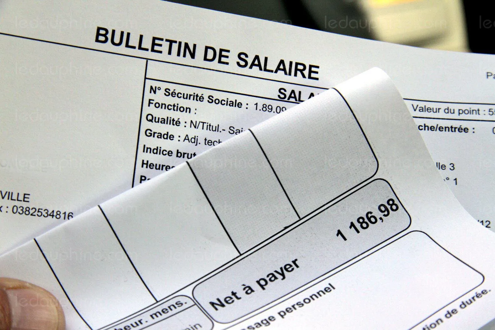 Une femme calcule son salaire brut et net avec une calculatrice, une fiche de paie et un carnet.