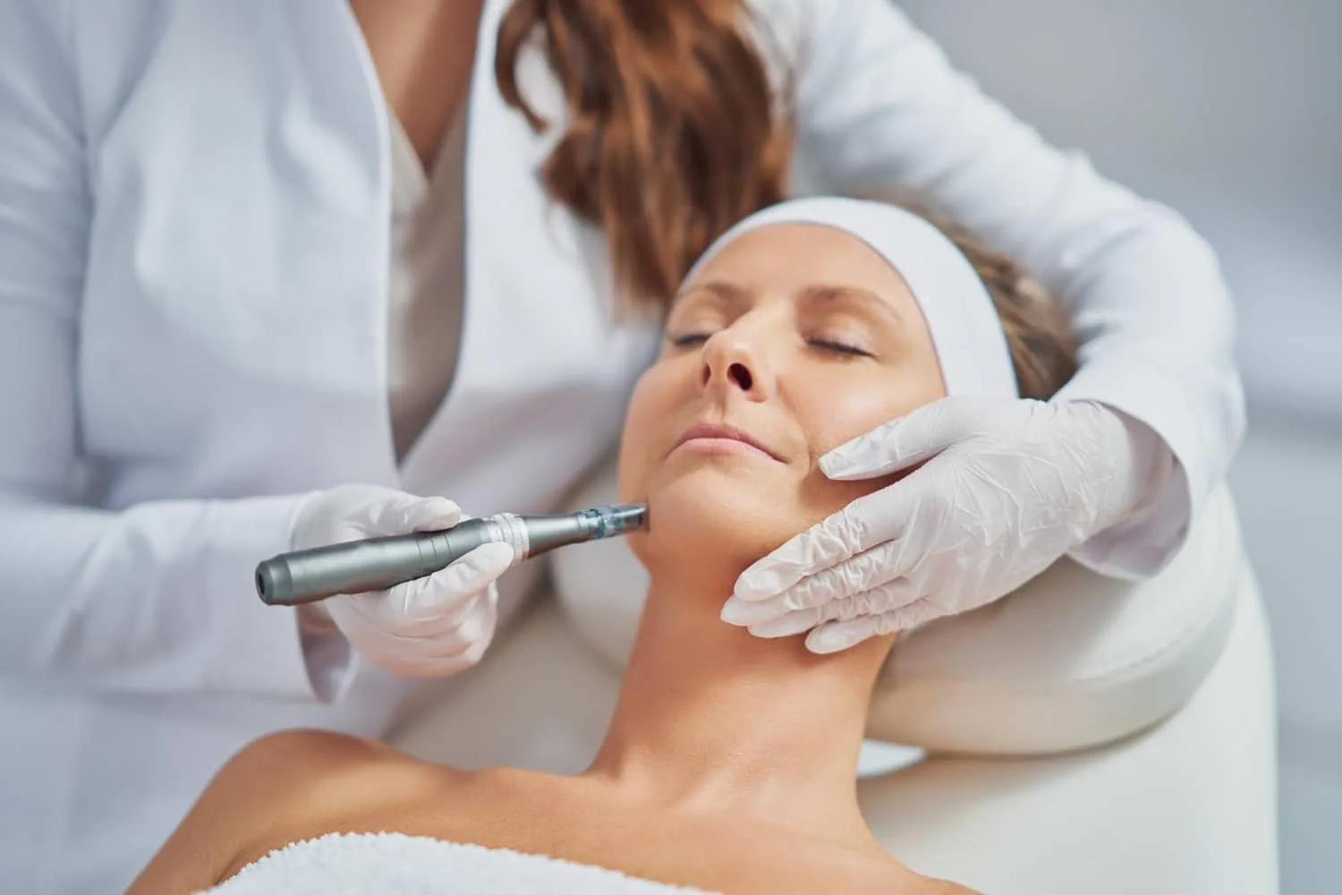Femme appliquant délicatement une crème hydratante sur son cou avec des gestes ascendants devant un miroir.