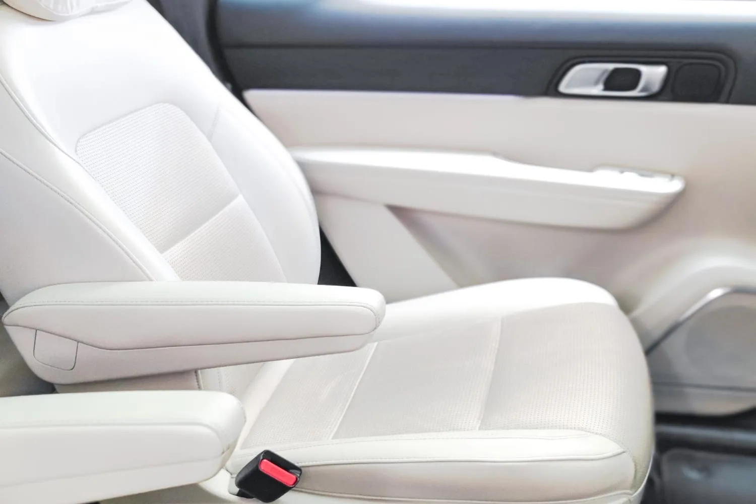 Siège de voiture en cuir blanc nettoyé avec une microfibre douce et un produit adapté au cuir automobile.