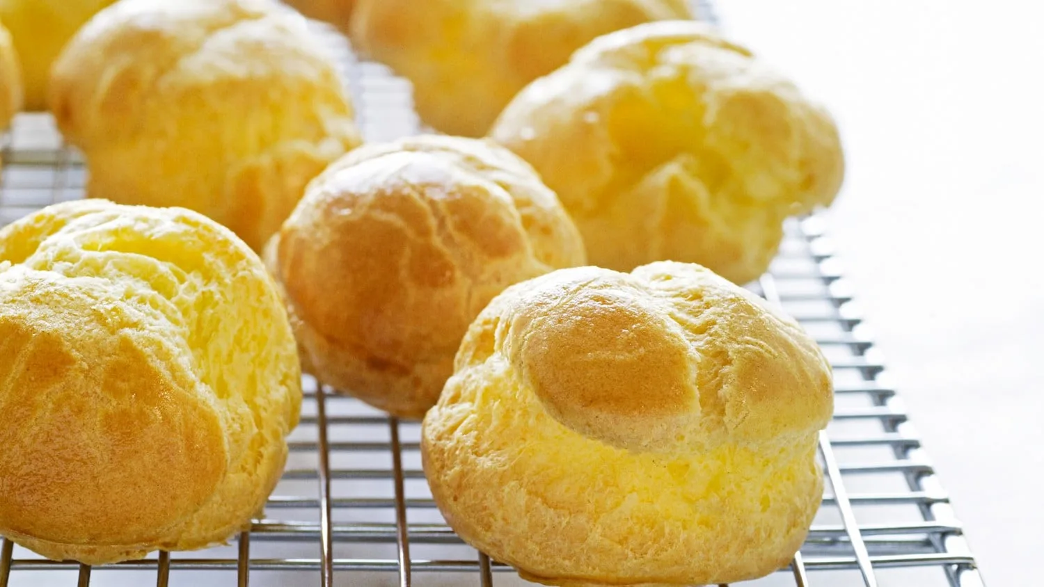 Plateau de choux pâtissiers dorés, garnis de crème et décorés de sucre glace.