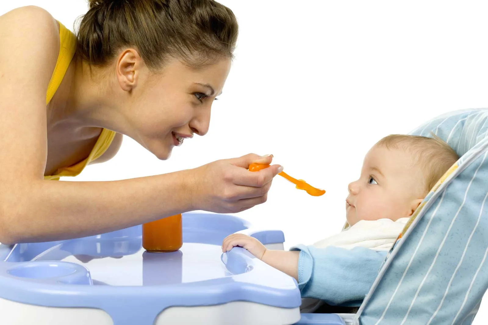 Jeune baby-sitter jouant avec deux enfants à une table, dans un salon lumineux et sécurisé.