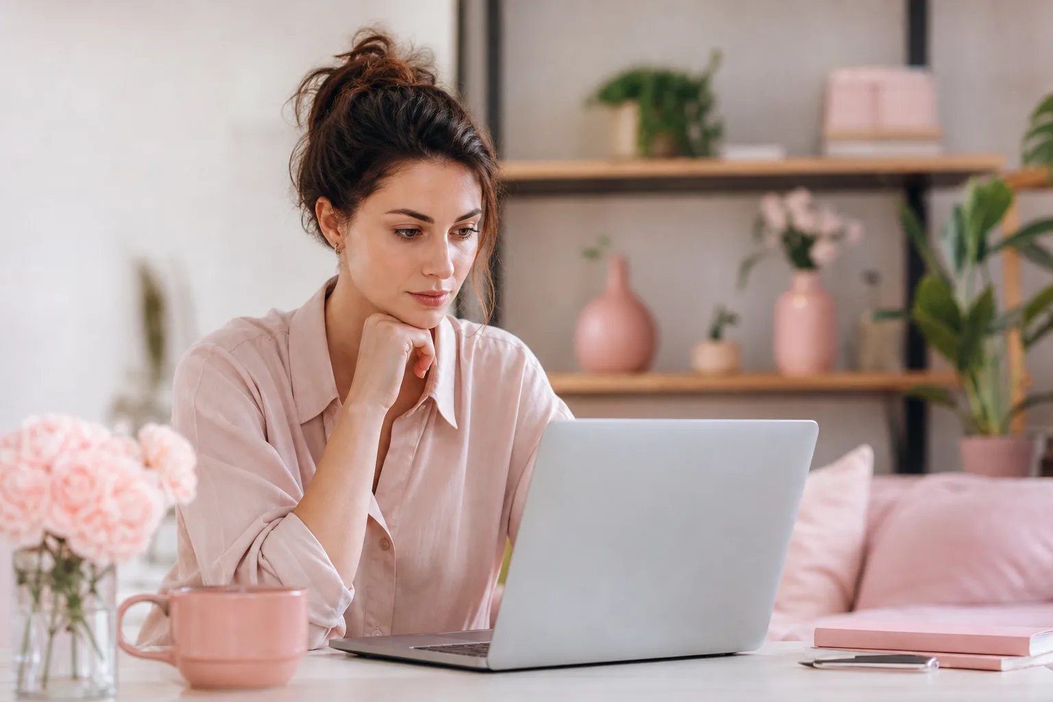 Femme consultant un chatbot IA sur son ordinateur pour organiser une demande complexe avec des notes à côté d’elle.