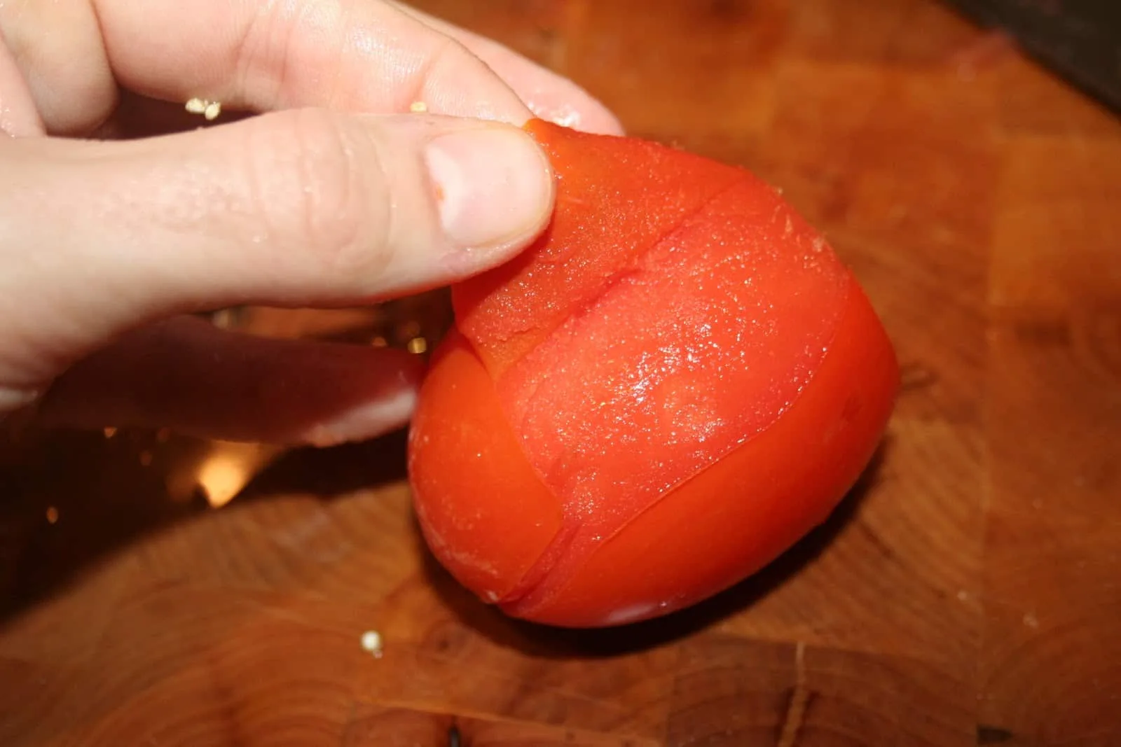 Tomates rouges entaillées en croix, plongées dans une casserole d’eau bouillante pour être pelées facilement.
