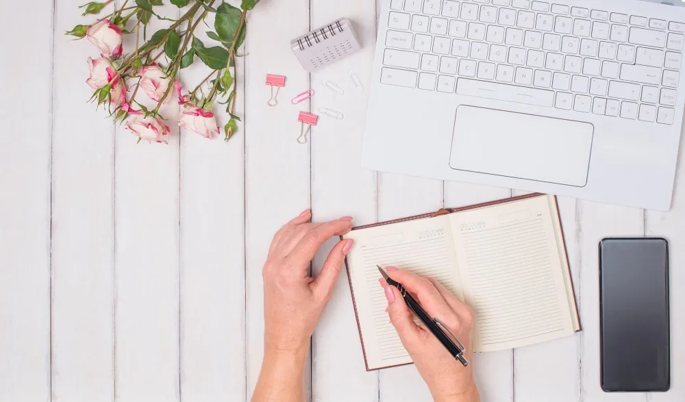 Femme rédigeant une lettre manuscrite à son bureau avec une enveloppe et un stylo élégant.