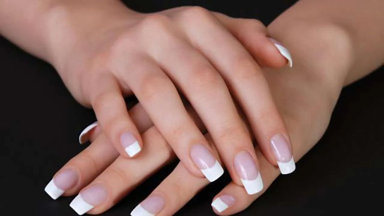 Manucure maison avec lime, vernis nude, base protectrice et outils de soin des cuticules sur une table claire.