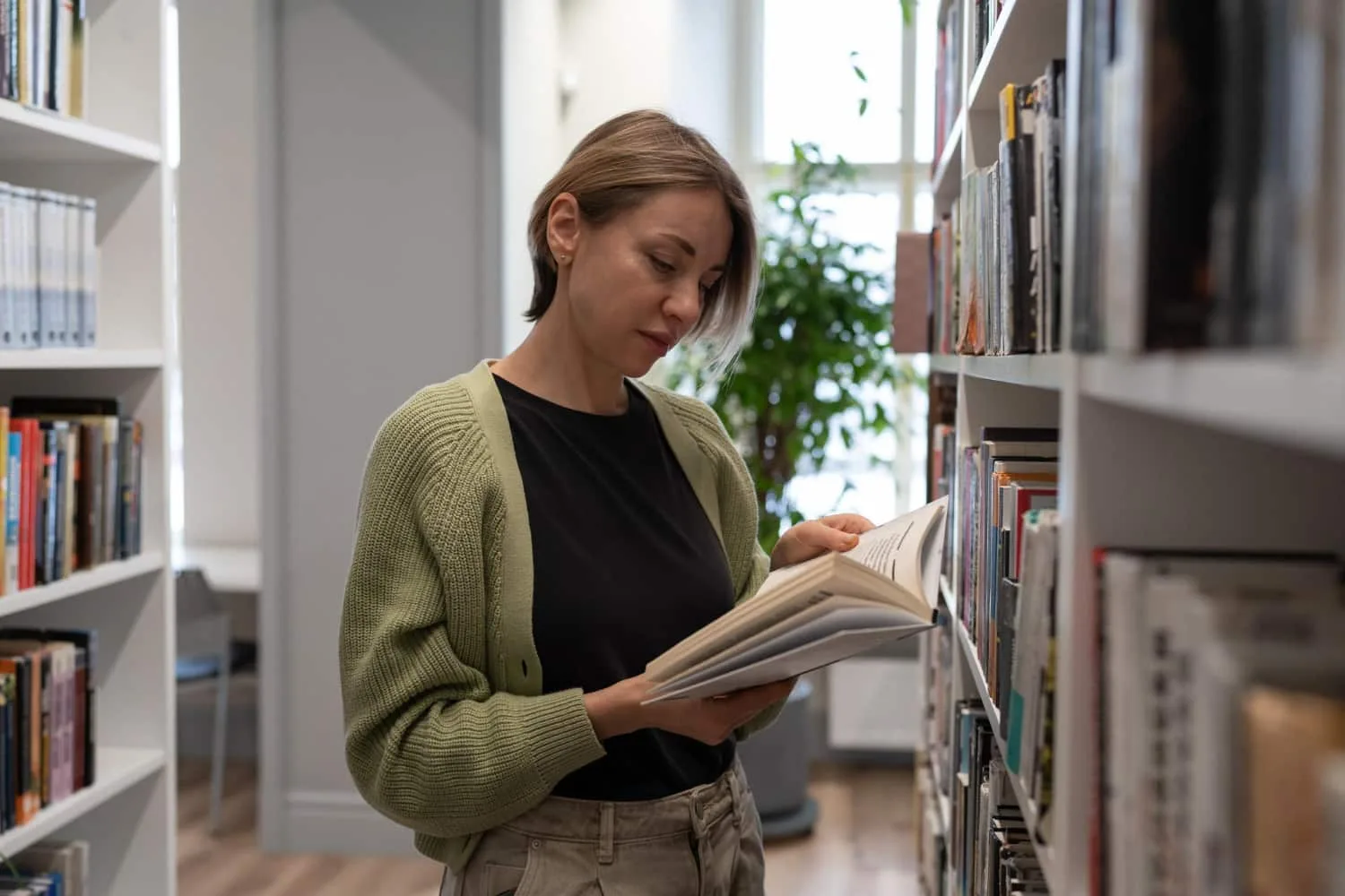 Une lectrice installée dans un fauteuil avec un livre ouvert et un carnet de notes, cherchant à retrouver sa motivation de lecture.