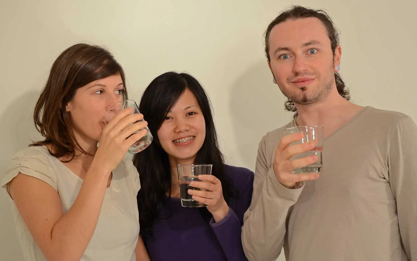 Femme préparant un repas riche en fibres avec légumes, fruits, céréales complètes et un verre d’eau pour favoriser le transit.