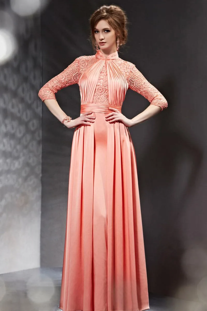 Femme portant une robe corail élégante avec accessoires dorés et maquillage lumineux.