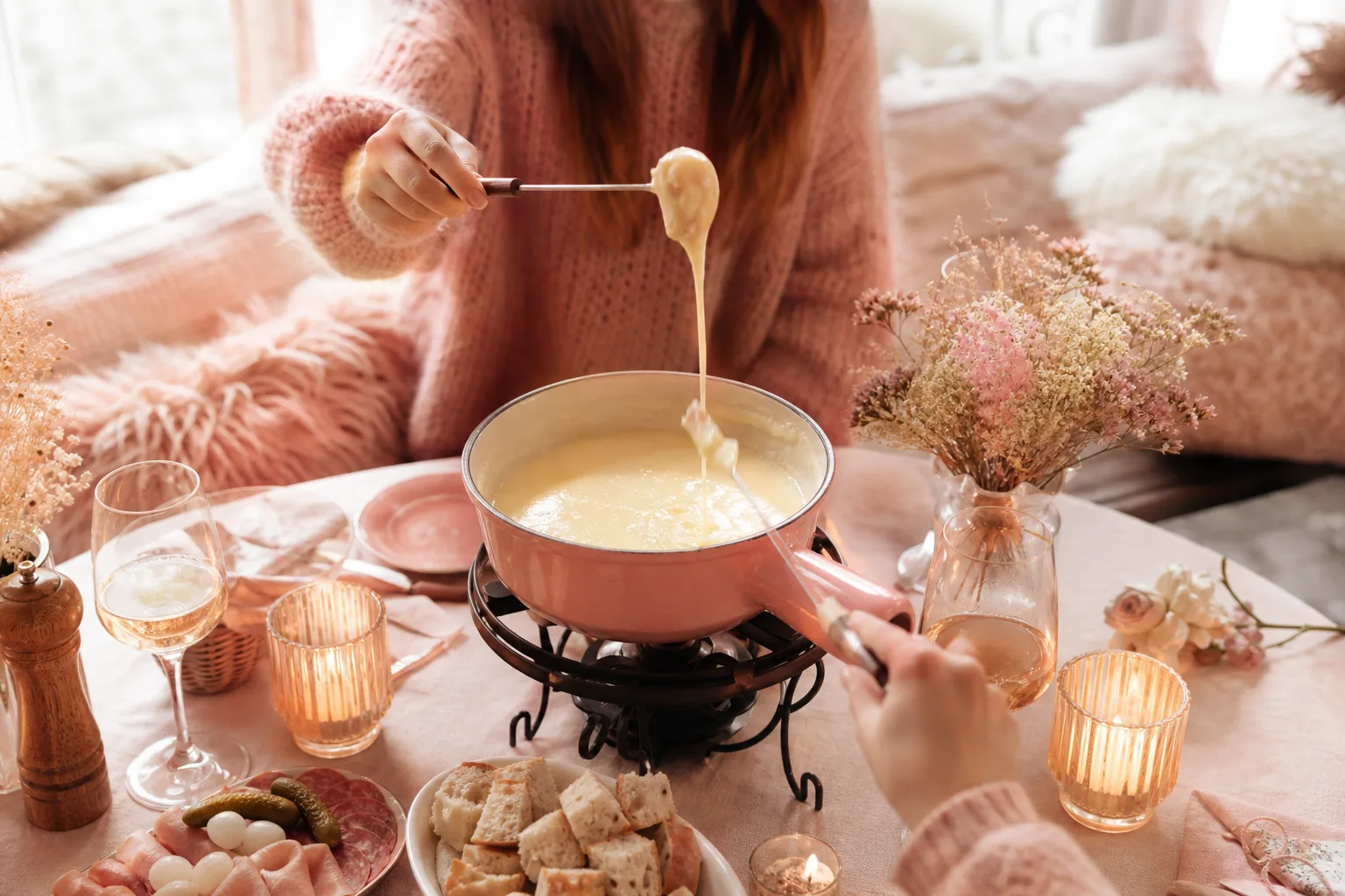 Caquelon de fondue savoyarde au fromage fondu servi avec des cubes de pain et des accompagnements hivernaux.