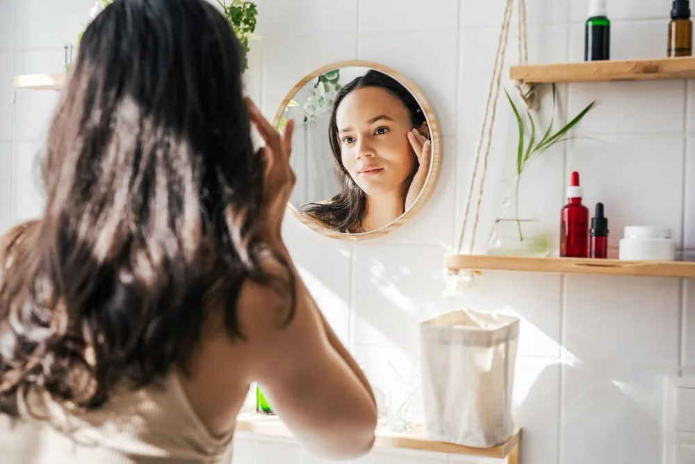 Flacons de soins visage avec sérum à la niacinamide, crème solaire et crème de nuit sur une coiffeuse lumineuse.