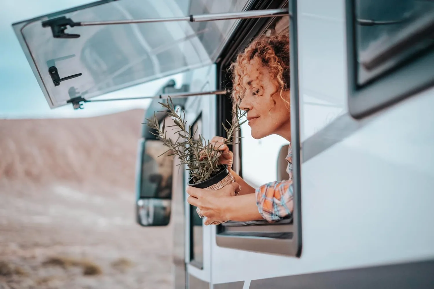 Famille avec deux enfants installée devant un camping-car garé dans un paysage naturel au coucher du soleil.