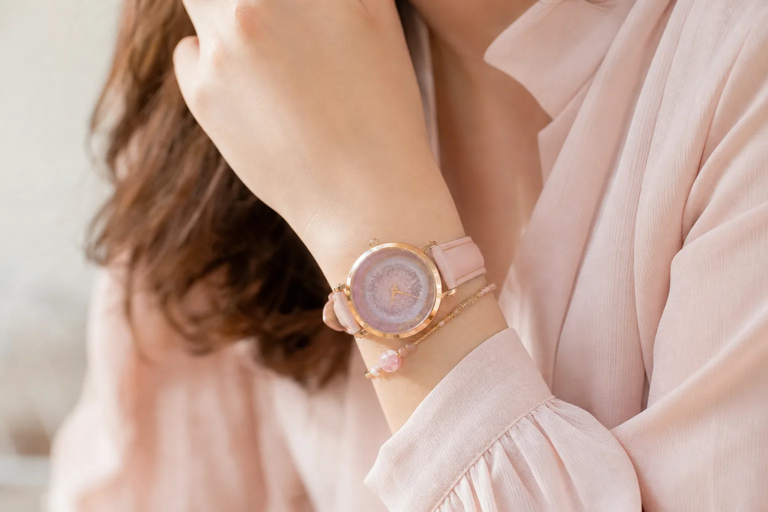 Montre fantaisie colorée au bracelet graphique portée au poignet avec des bijoux fins dorés.
