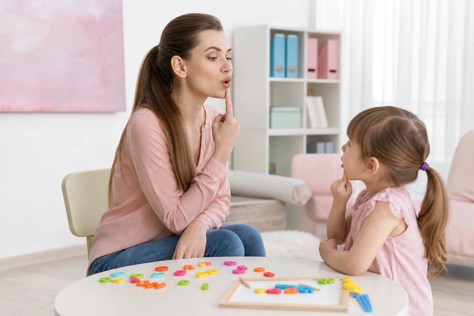 Une orthophoniste échange avec un enfant autour de jeux et d’images lors d’une séance de langage.