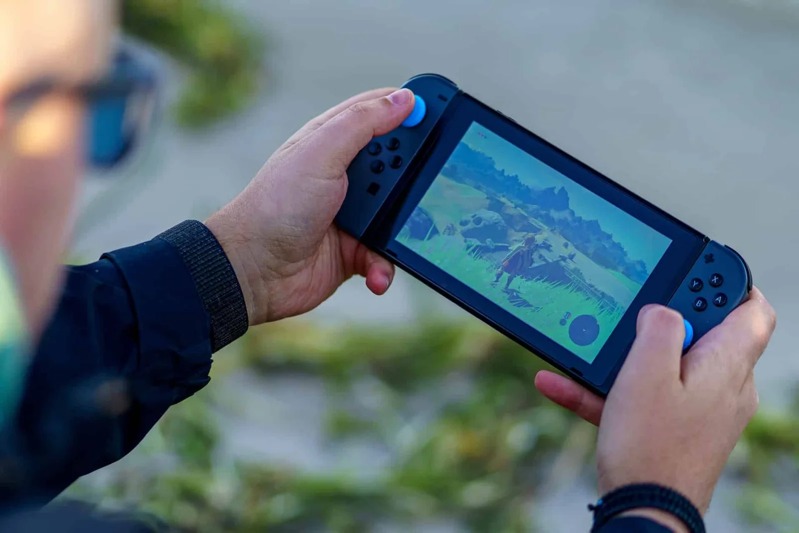 Joueuse découvrant un jeu vidéo indépendant coloré sur une console portable dans un intérieur cosy.