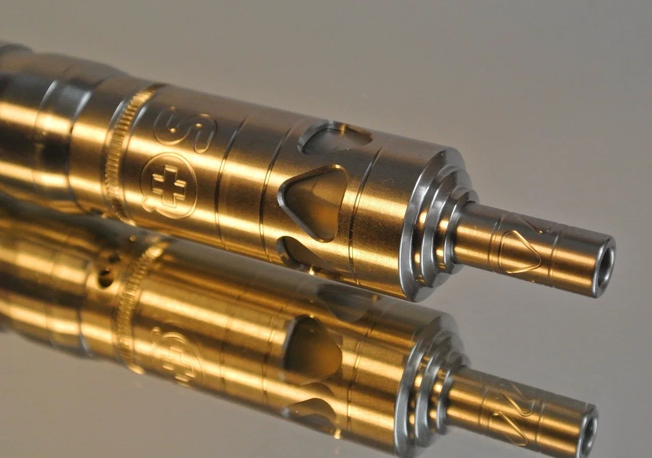 Clearomiseur MTL compact posé près d’un flacon d’e-liquide et de résistances de rechange.