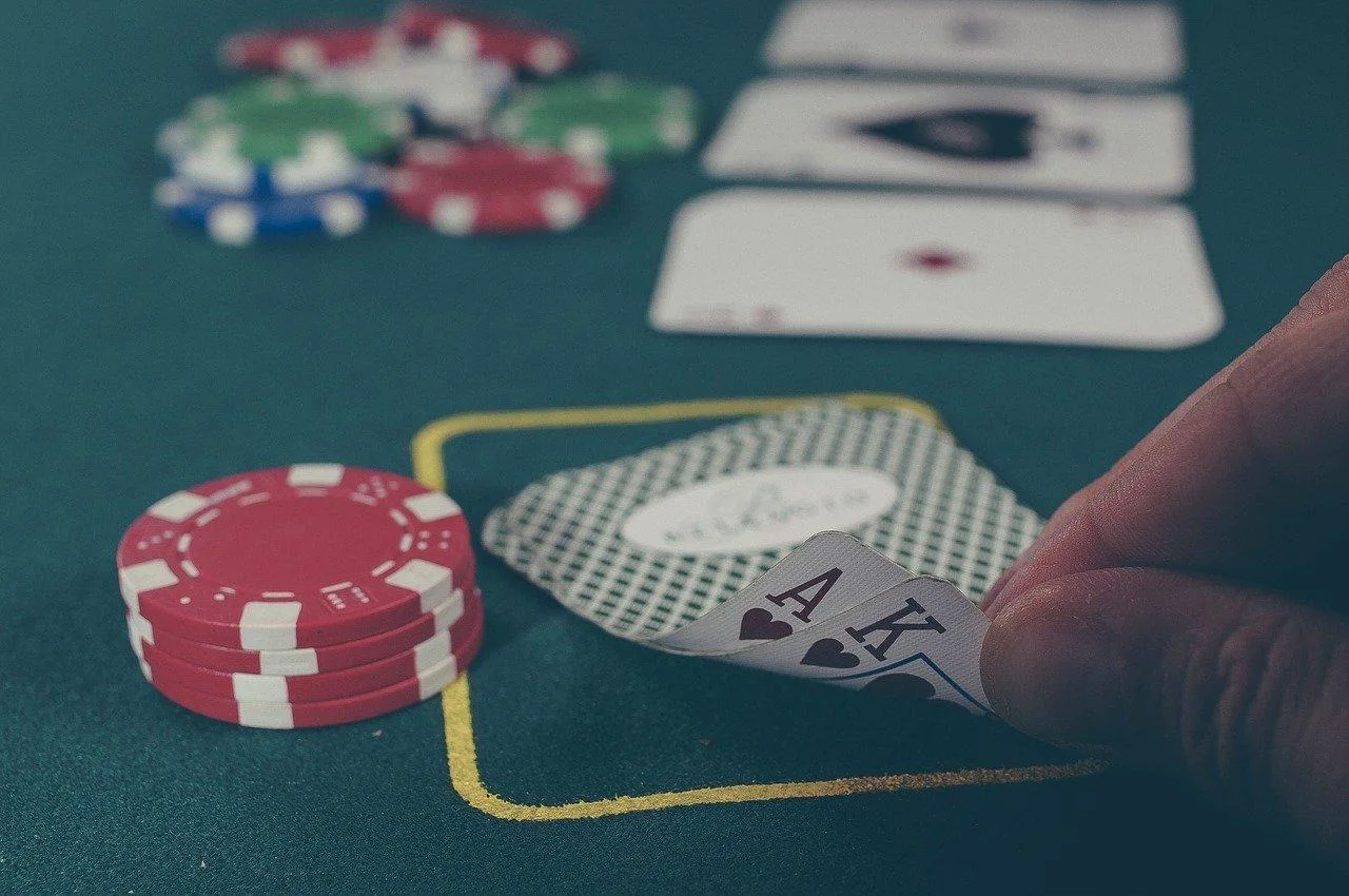 Joueuse consultant les règles du blackjack sur une table de casino avec cartes, jetons et croupier en arrière-plan.