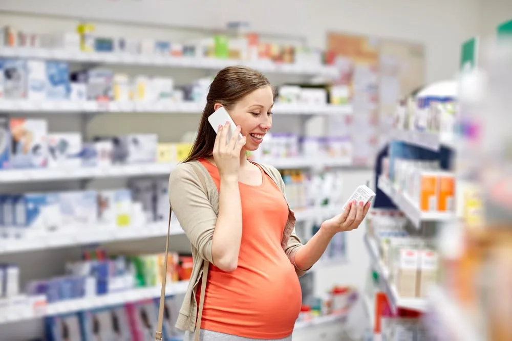Calendrier de grossesse posé près de petits chaussons de bébé et d’un test de grossesse, pour planifier l’arrivée de bébé.